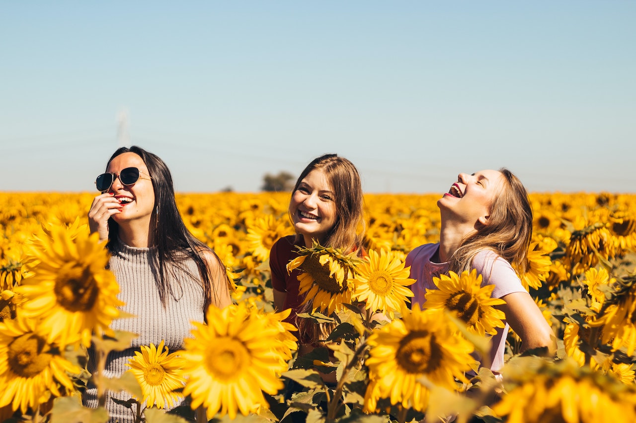 friends in sunflower field smiling laughing