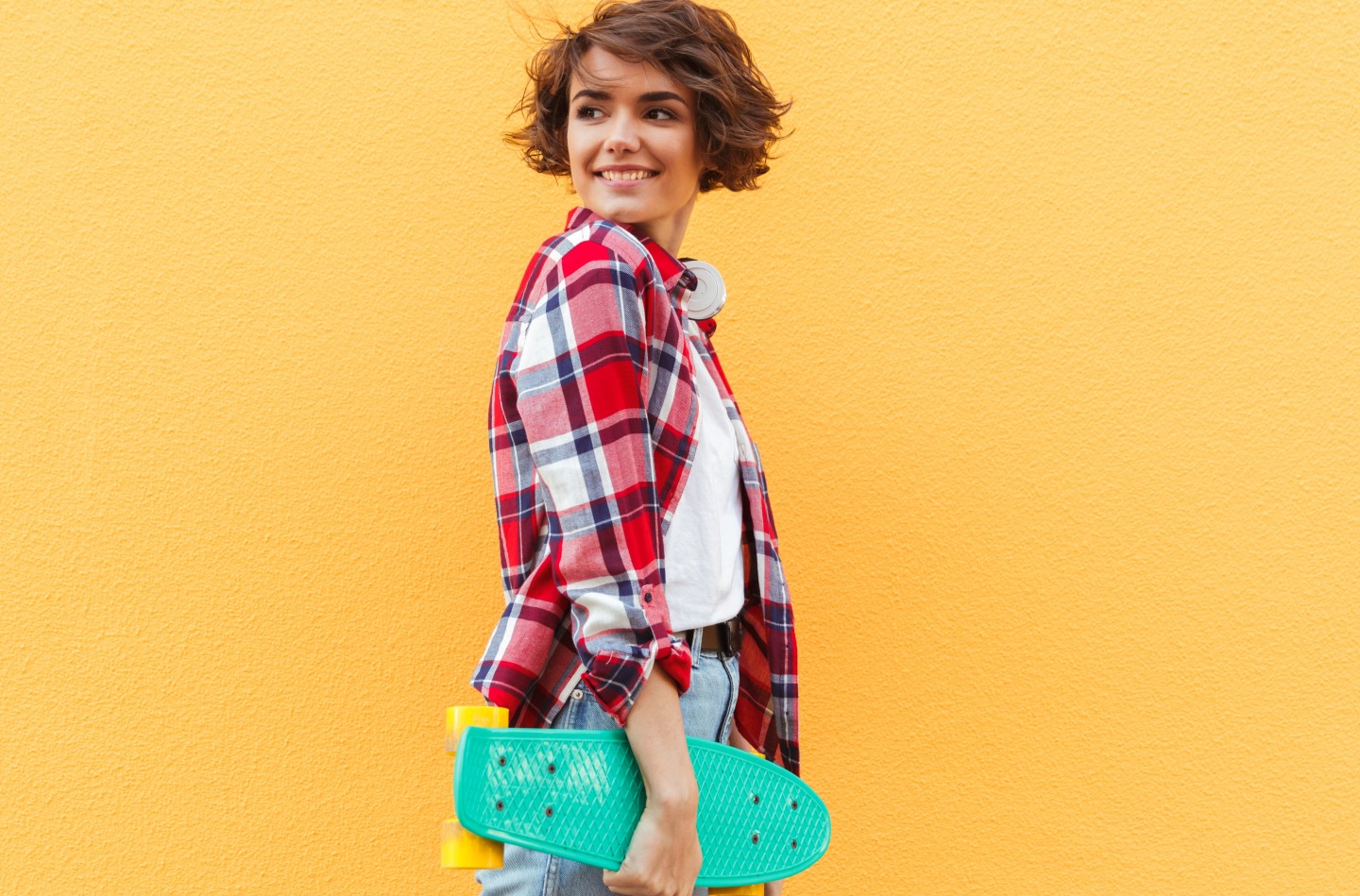woman-smiling-yellow-wall-skateboard