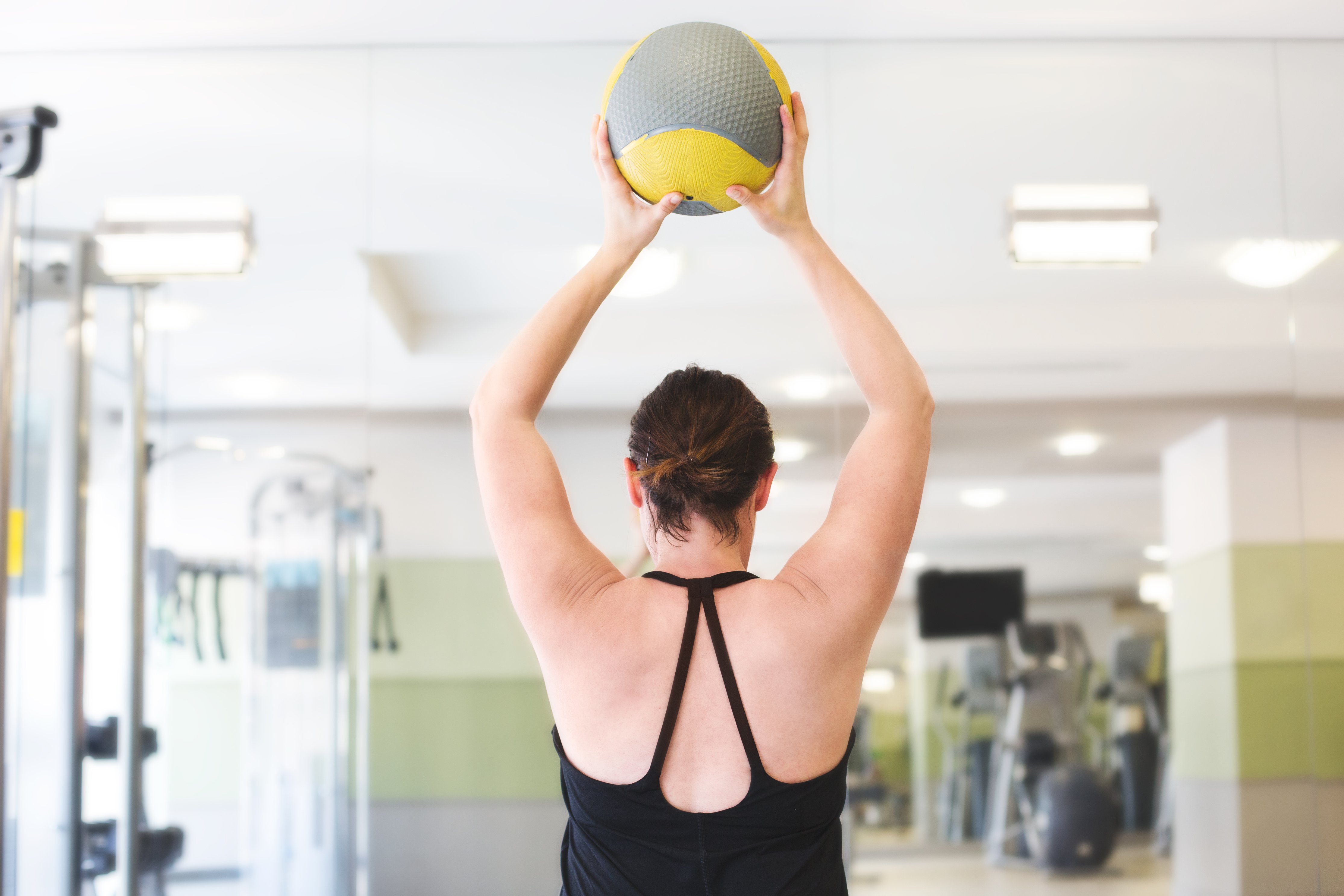 woman lifting fitness ball gym