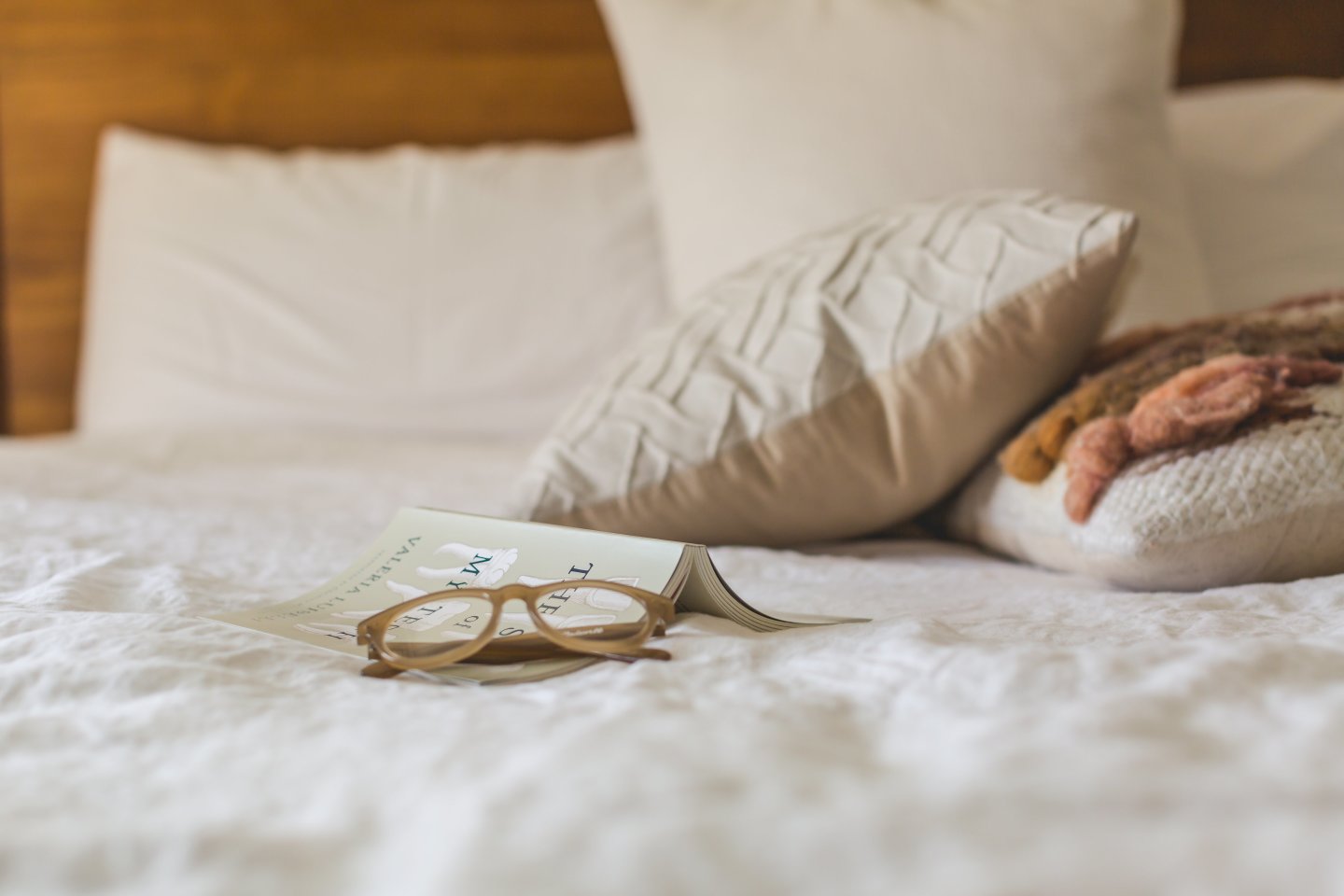 glasses, book, pillow on bed