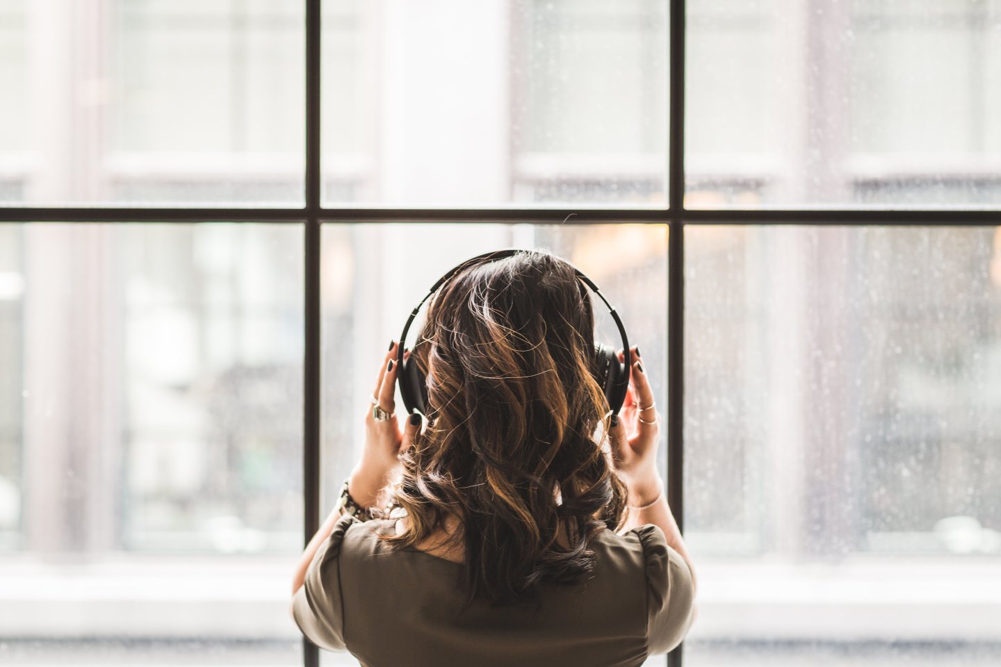 woman looking out window wearing headphones
