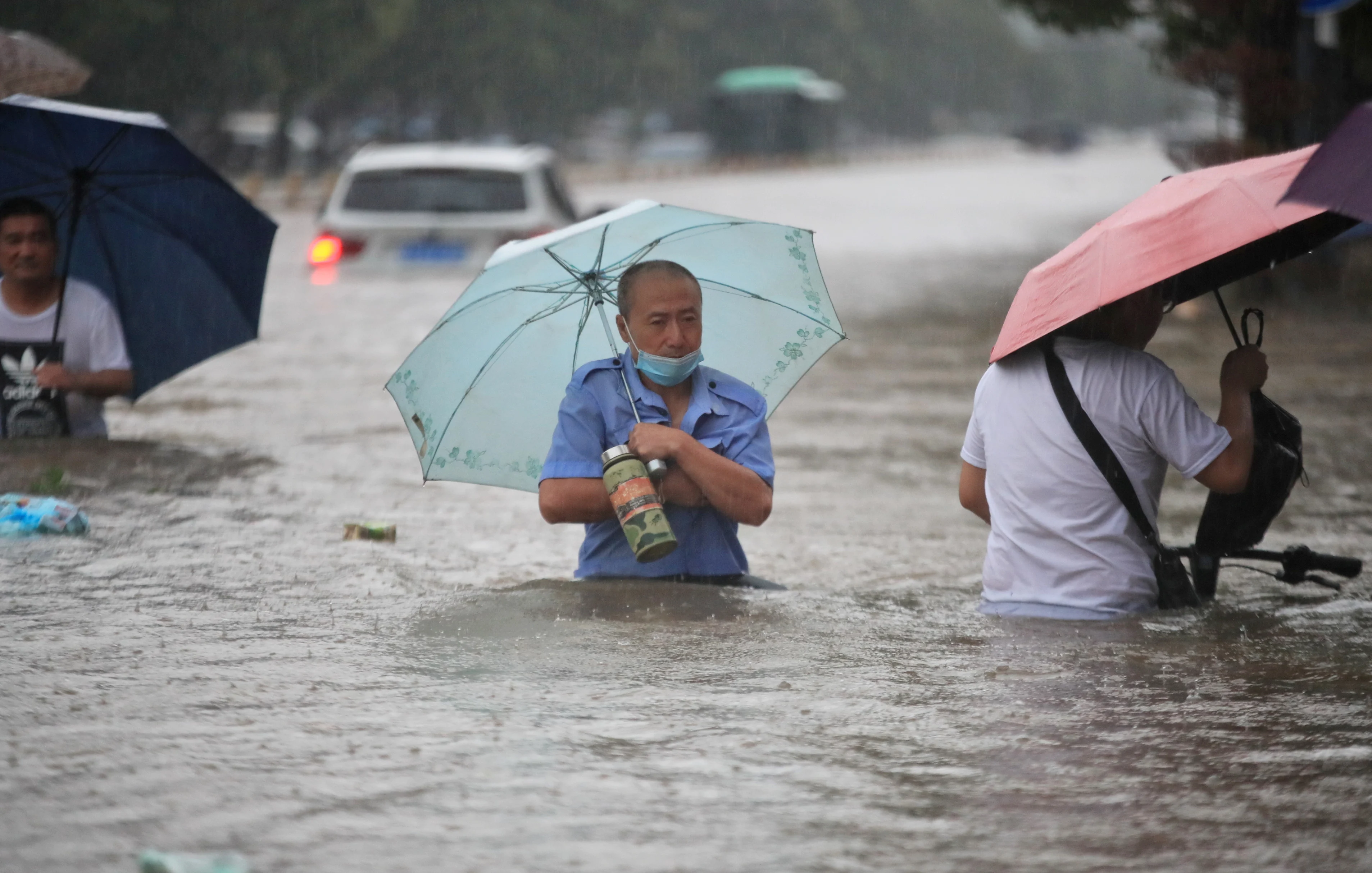Residents wade through floodwaters on a flooded road amid heavy rainfall in Zhengzhou, Henan province, China July 20, 2021. China Daily via REUTERS