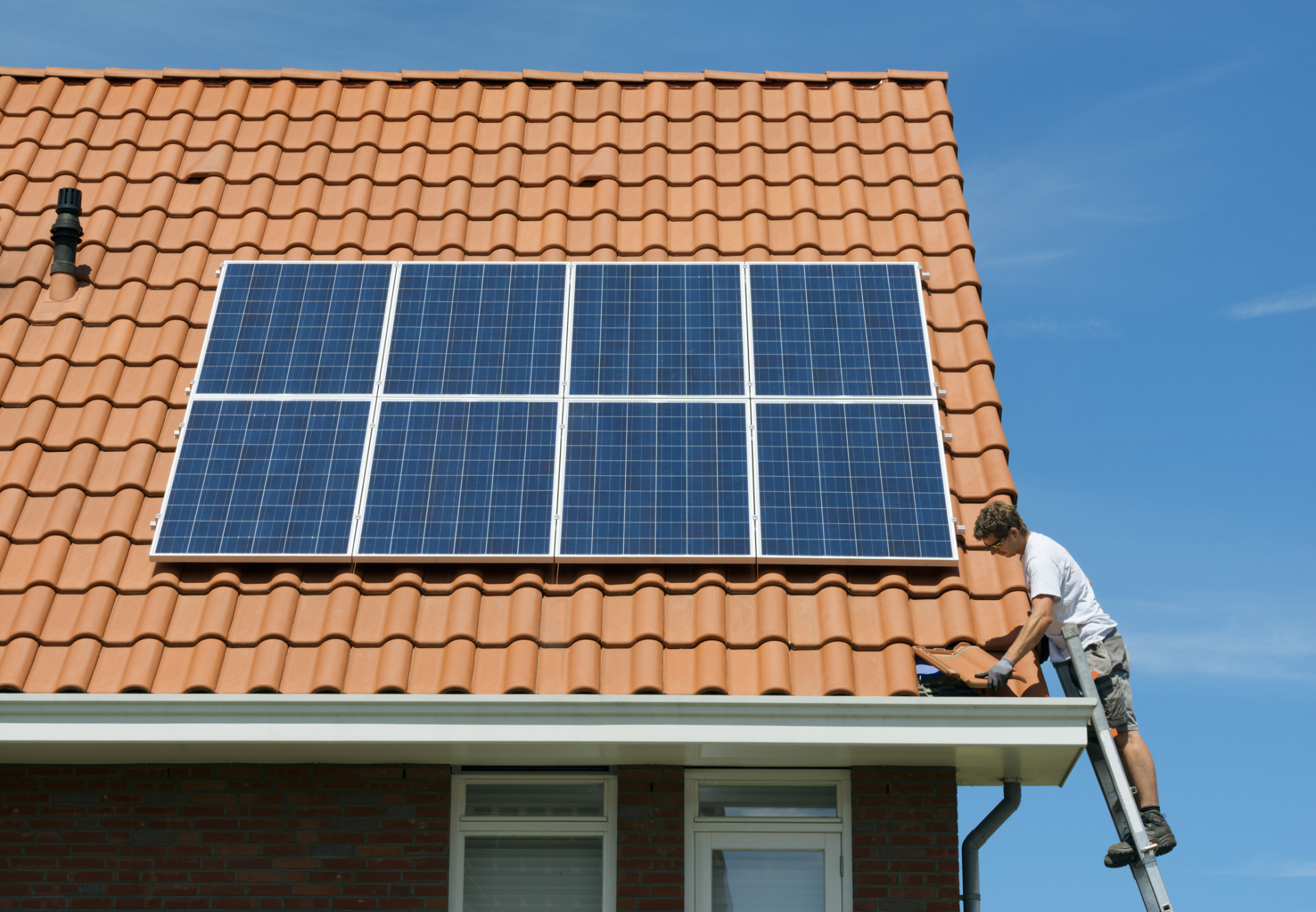 A worker installing solar panels on the roof of a new home. (Mischa Keijser. Cultura. Getty Images)