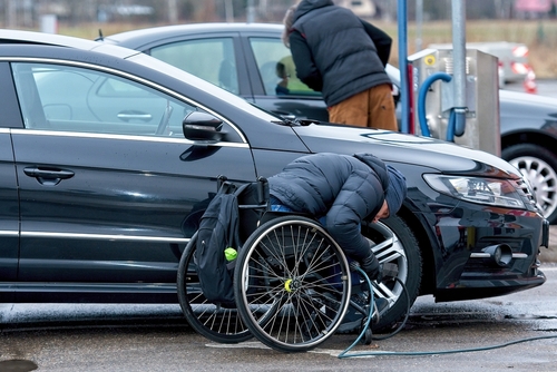 Driver filling his tire with air using a compressor