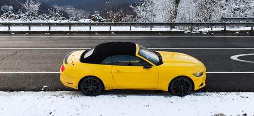 Yellow Ford Mustang roadside with snow