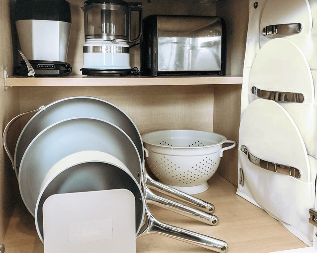 Inside cabinet storage with ceramic pots, pans, lids, and more