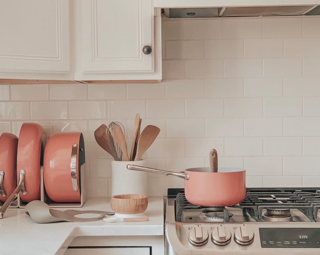 Countertop storage featuring red ceramic pots and pans from Caraway