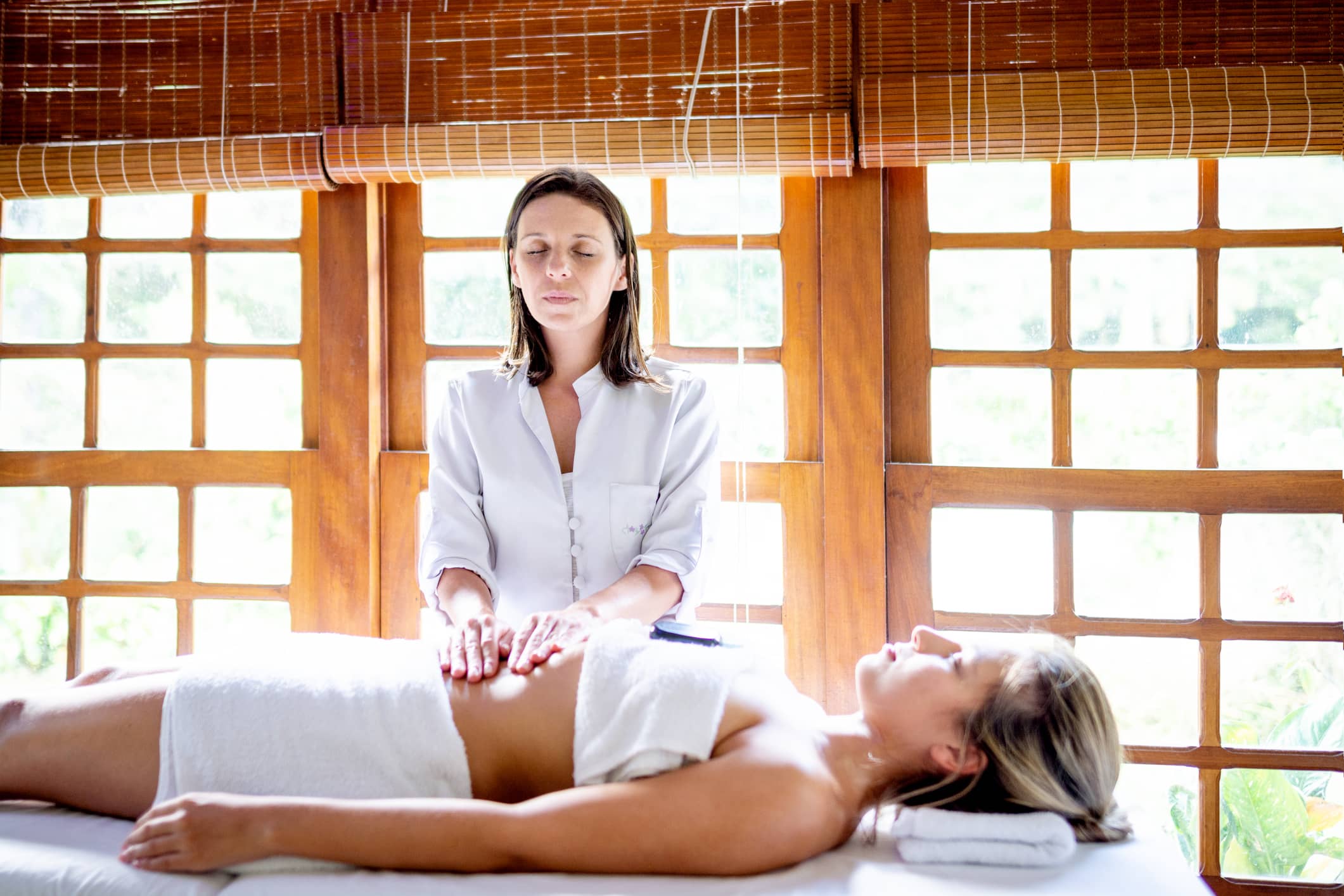 Woman having a stomach massage from a massage therapist to help manage her stress levels and reduce bloating in her stomach’