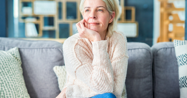 Woman sitting on a couch wondering when does menopause brain fog end