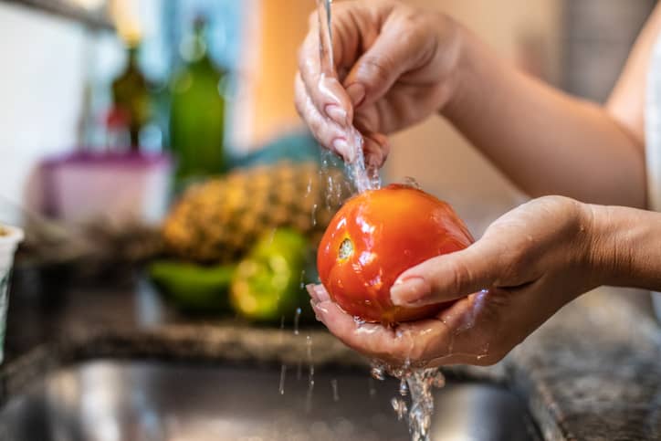 Someone washing a tomato before eating