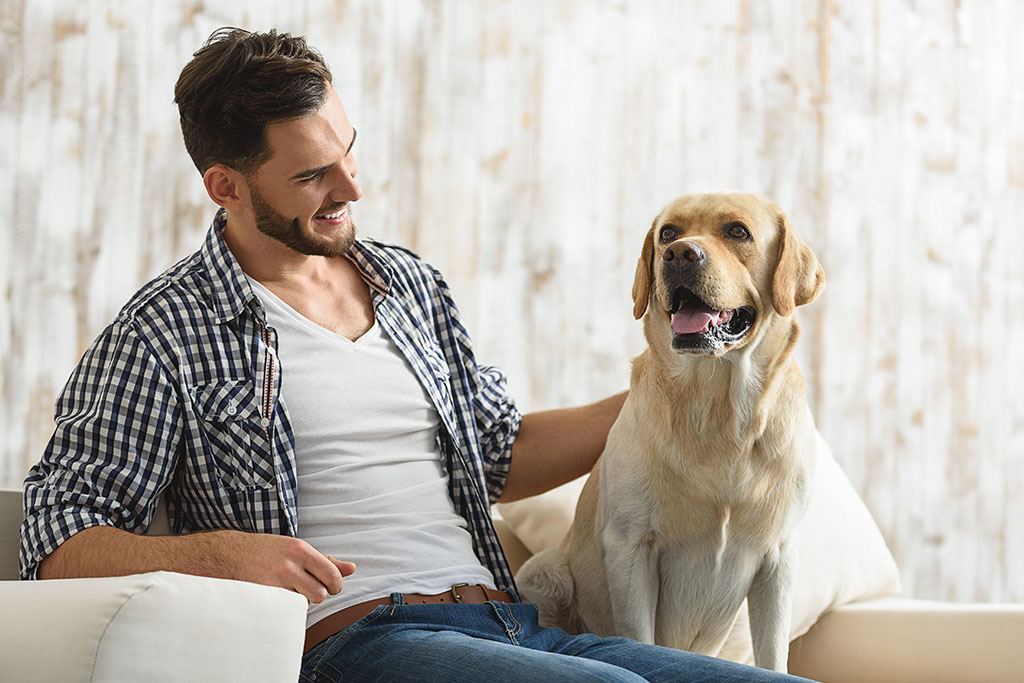 young bearded guy stroking his dog indoors
