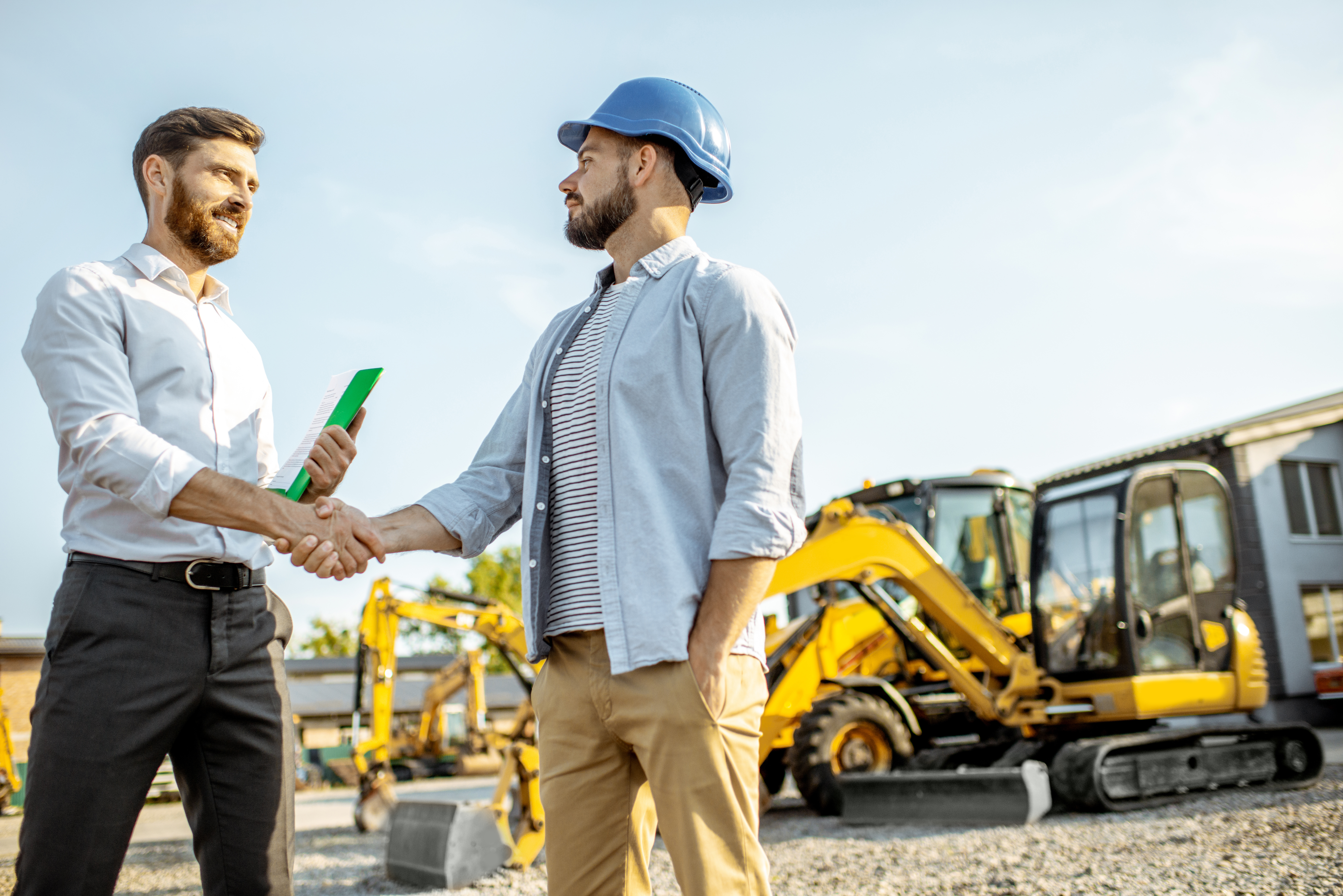 Builder choosing heavy machinery for construction with a sales consultant standing with some documents