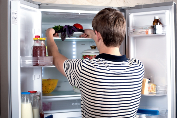 Vy innuti side by side kylskåp - man tar ut mat