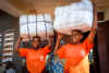 Women holding bales of insecticide-treated bednets provided by the Against Malaria Foundation.