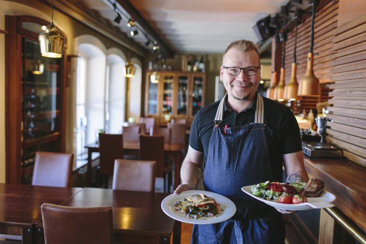 Oululaisen Toripolliisi-ravintolan toinen omistaja Antti Sotaniemi esittelee kahta lautasannosta maineikkaan ravintolan sisätiloissa.